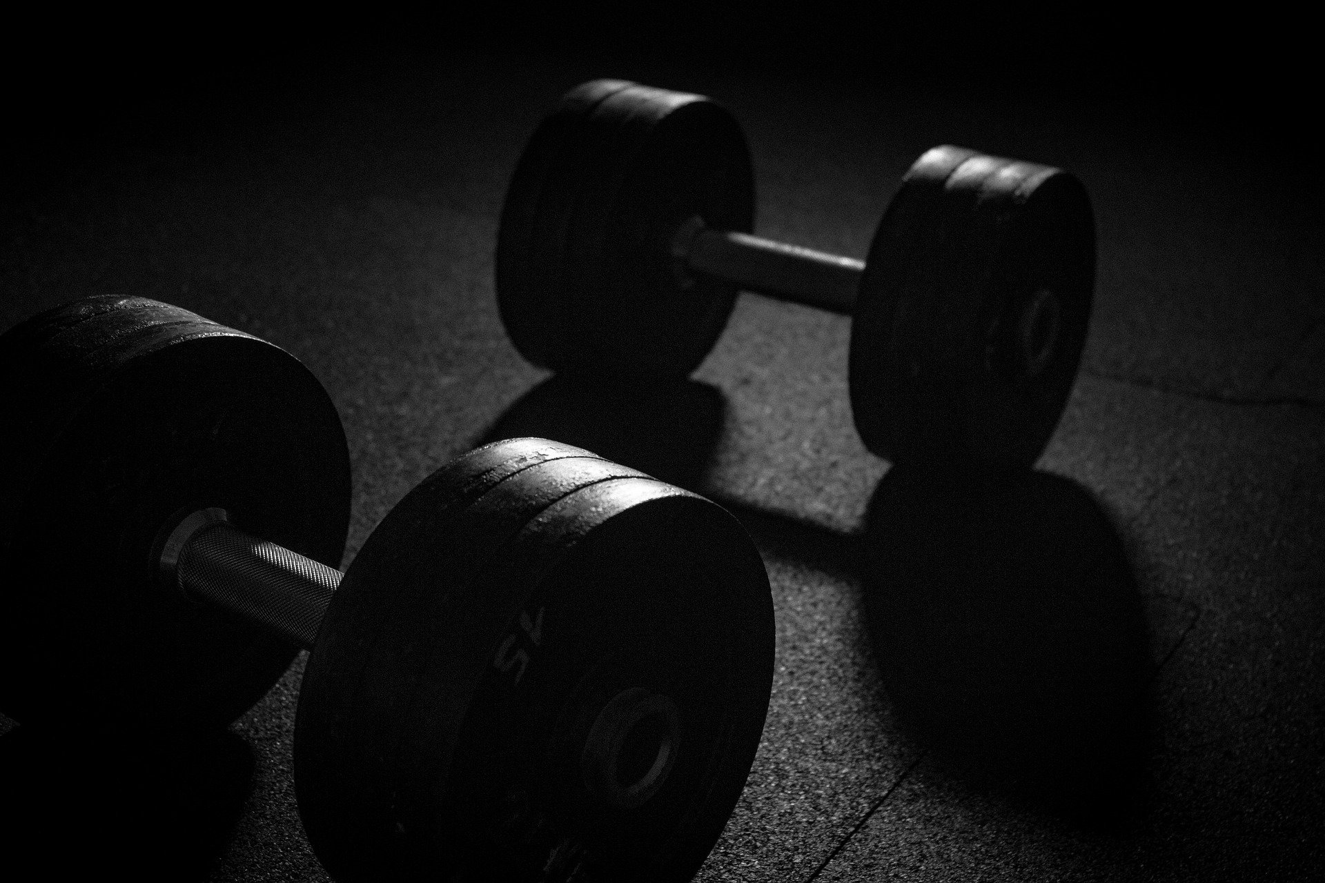 Two dumbbells on a gym floor. The picture has a dark tone to it: How To Throw a Baseball - FAST! [MindfuseBaseball.com]